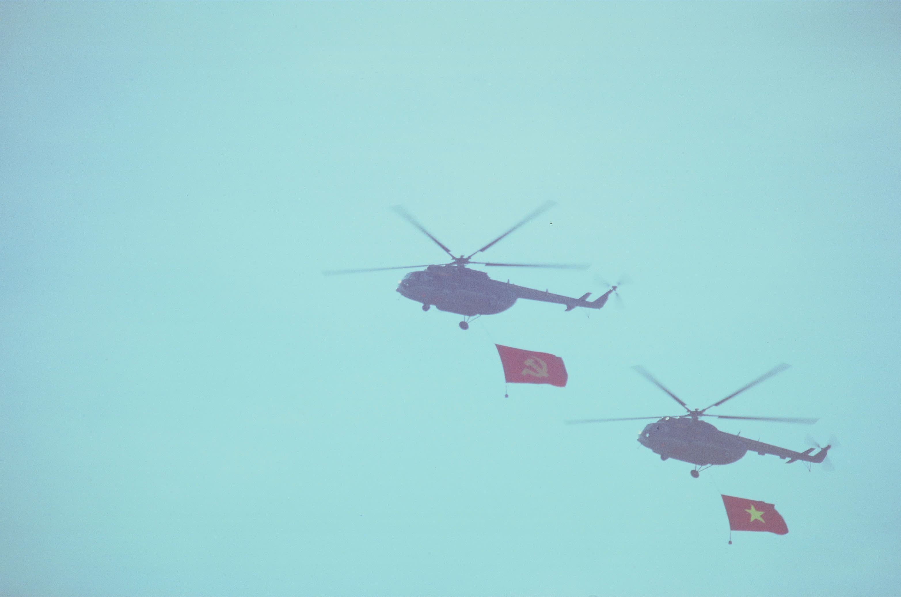 Helicopters carrying red flags during an April 2025 practice flight over Saigon