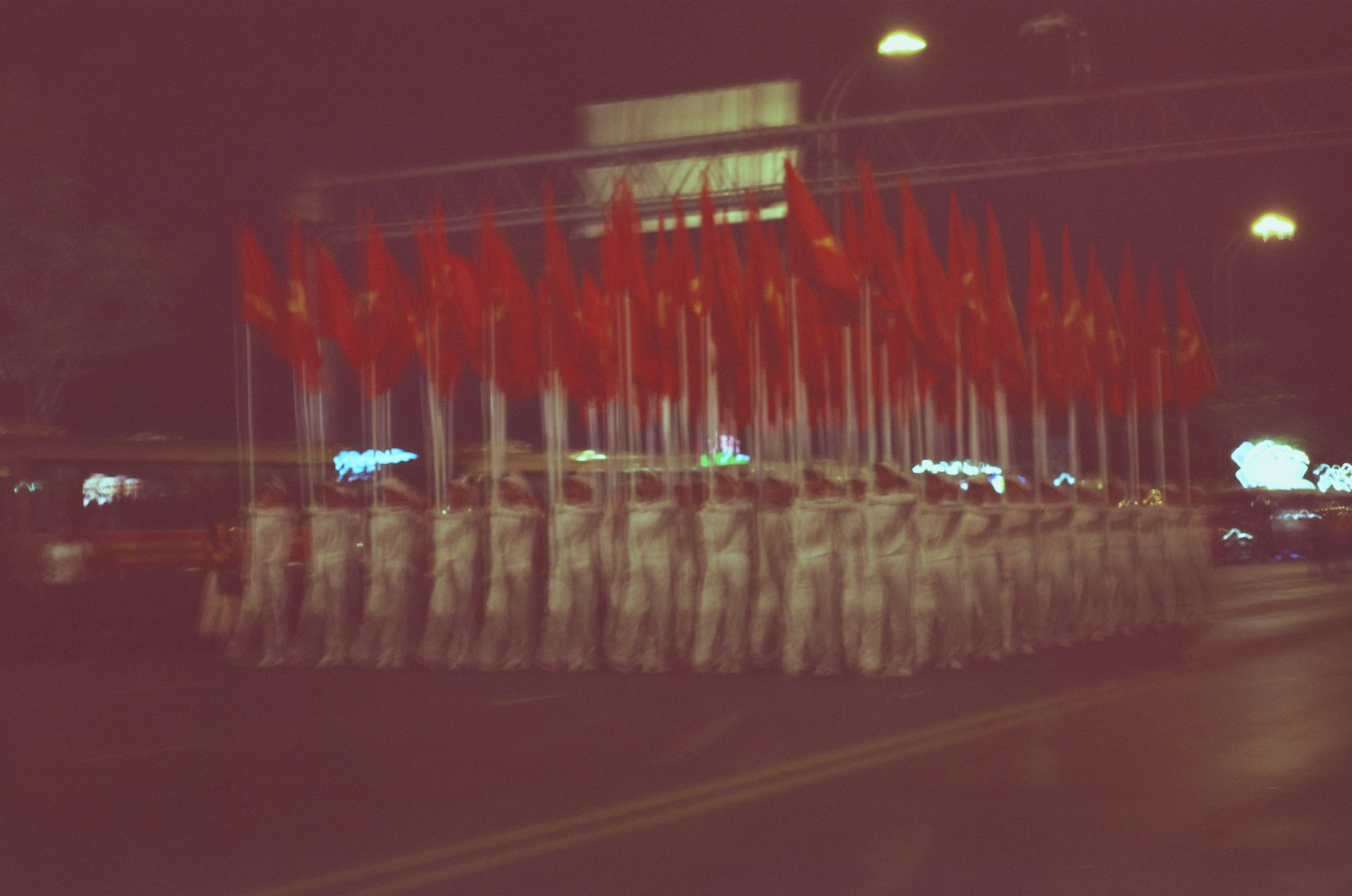 A nighttime parade formation carrying Vietnamese flags through Saigon